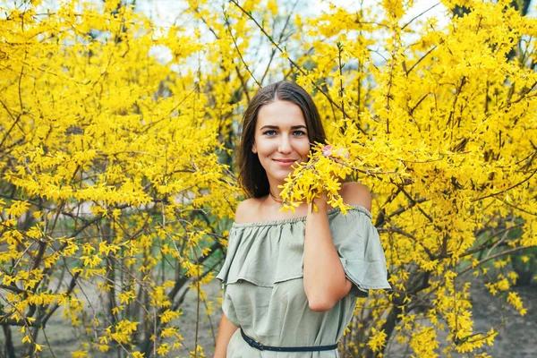 Feliz joven sonriente con flores de primavera en el jardín — Foto de Stock