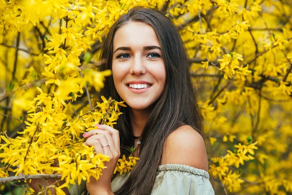 Feliz joven sonriente con flores de primavera en el jardín — Foto de Stock