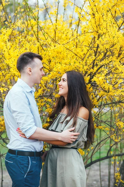 Unga lyckliga par i kärlek utomhus. Man och kvinna på en promenad i en våren blommande park — Stockfoto