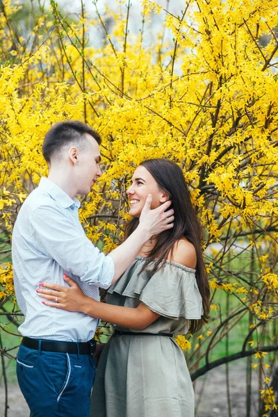 Jonge gelukkige paar verliefd buitenshuis. Man en vrouw op een wandeling in een bloeiende park voorjaarsbijeenkomst — Stockfoto