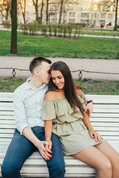 Šťastný mladý pár v lásce sedí na lavičce v parku a objímání — Stock fotografie