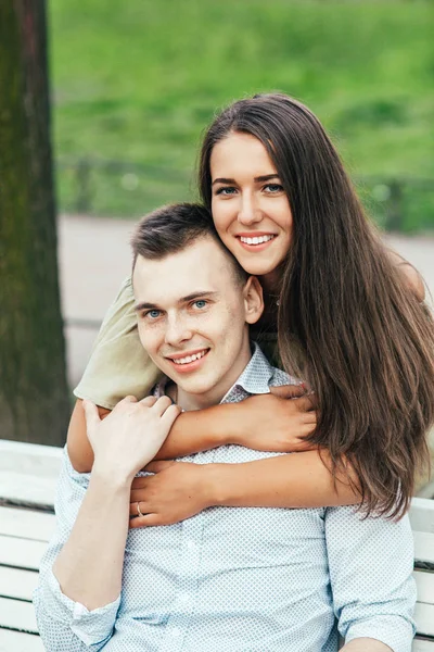 Щаслива молода пара в любові сидить на лавці парку і обіймає — стокове фото