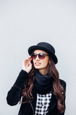 Yüzünde gülümseme ile kentsel kız gülümsüyor. Moda kız açık havada eğleniyor bir rock siyah stil giyen portresi