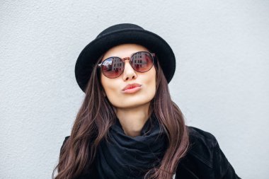 Yüzünde gülümseme ile kentsel kız gülümsüyor. Moda kız açık havada eğleniyor bir rock siyah stil giyen portresi