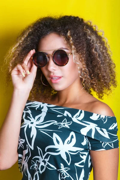 Portrait of a young afro american woman in sunglasses. Yellow background. Lifestyle. — Stock Photo, Image