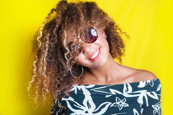 Portrait of a young afro american woman in sunglasses. Yellow background. Lifestyle. — Stock Photo, Image