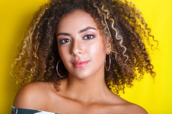 Retrato de beleza da jovem menina afro-americana com penteado afro. Menina posando no fundo amarelo, olhando para a câmera . — Fotografia de Stock