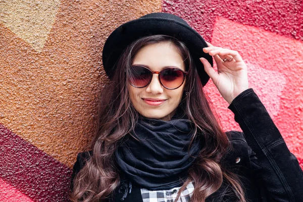 Yüzünde gülümseme ile kentsel kız gülümsüyor. Moda kız açık havada şehir sokakta eğleniyor bir rock siyah stil giyen portresi — Stok fotoğraf