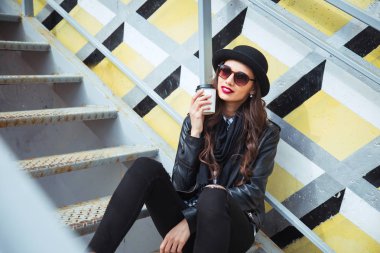 Şık kadın bir şehir sokakta oturan ve kahve veya çay içme .