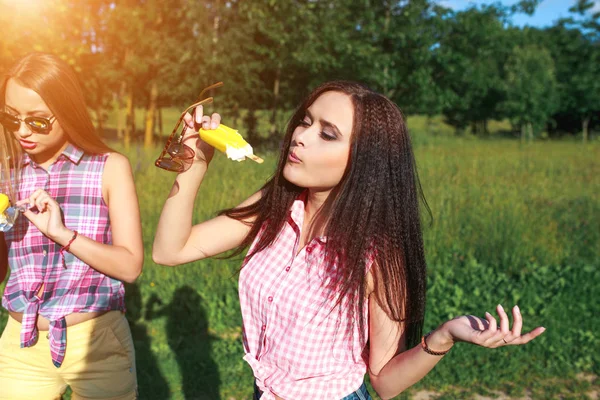 Tři mladé ženy jíst zmrzlinu v parku na horkém letním dni — Stock fotografie