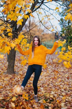 Güzel mutlu kadın sonbahar parkında eğleniyor.