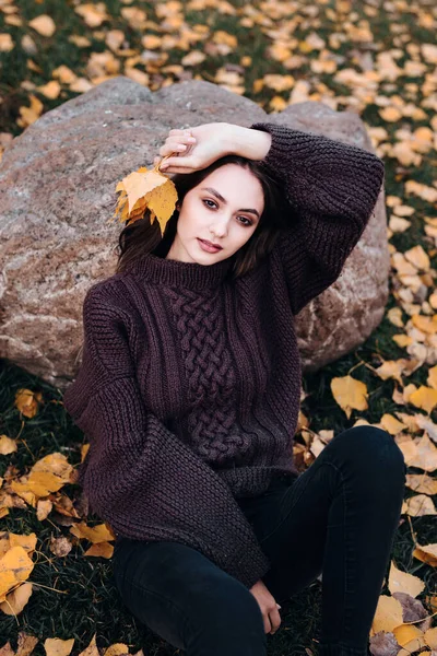 Melancholic beautiful young woman sitting in autumn park — Stock Photo, Image