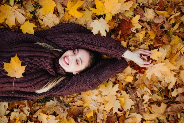Młoda kobieta leżąca na jesiennych liściach i ciesząca się przyrodą — Zdjęcie stockowe