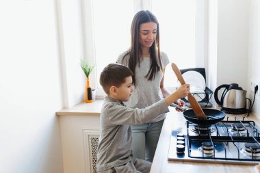Mutfakta mutlu bir aile. Anne ve çocuk birlikte kahvaltı hazırlıyorlar.