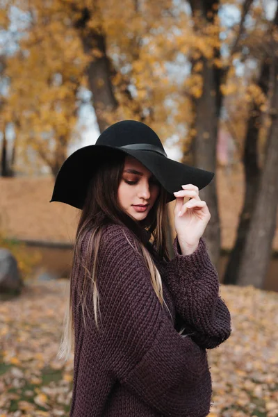 Outdoor fashion photo of young beautiful woman in black hat in autumn park — Stock Photo, Image
