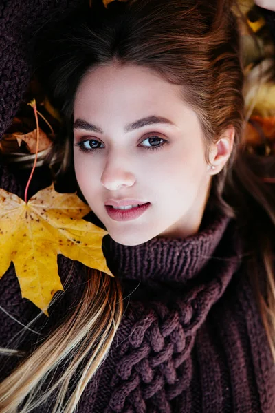 Retrato de cerca de una hermosa chica acostada sobre hojas caídas de arce otoño — Foto de Stock