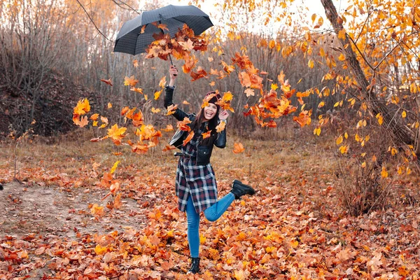 公園で紅葉と遊ぶ若い女性。秋の雨 — ストック写真