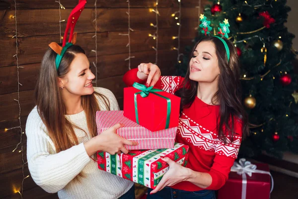 Két barátnő nevet és karácsonyi ajándékokat oszt meg otthon. — Stock Fotó