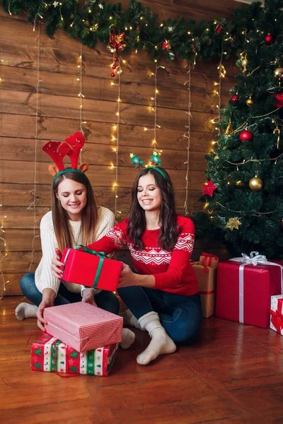 Δύο όμορφες γυναίκες κρατώντας χριστουγεννιάτικα δώρα κοντά σε ένα χριστουγεννιάτικο δέντρο — Φωτογραφία Αρχείου