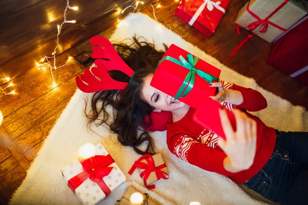 Hermosa mujer divertida con regalos de Navidad tumbada en el suelo y tomando selfie. Feliz Navidad y Feliz Año Nuevo — Foto de Stock