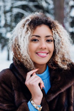 Kış parkındaki gülümseyen Afrikalı Amerikalı genç kızın güzel portresi.