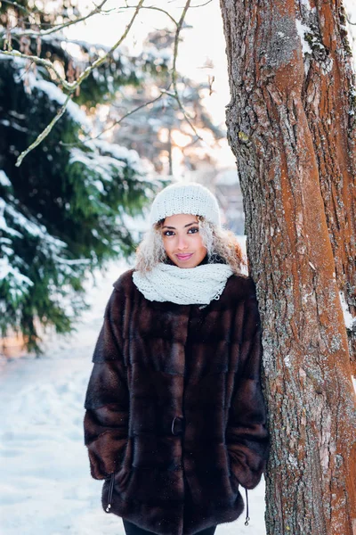 Niña afroamericana vistiendo en abrigo de piel y sombrero blanco de punto en el parque en invierno día soleado —  Fotos de Stock