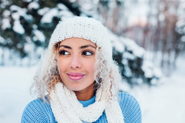 Πορτρέτο της νεαρής Αφρο-Αμερικανίδας που φοράει καπέλο, μπλε πουλόβερ ποζάροντας στο χειμερινό πάρκο. — Φωτογραφία Αρχείου