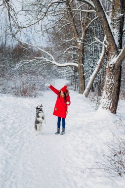 Genç kadın ile onun Husky köpek kış parkta oynarken