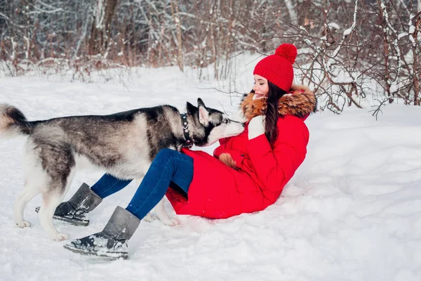 Menina bonita está brincando com o cão na neve no parque de inverno , — Fotografia de Stock