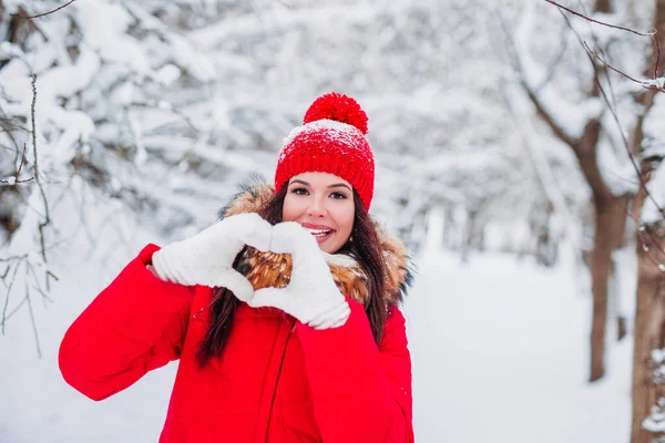 Mujer joven bastante romántica haciendo un gesto de corazón con los dedos en el fondo de invierno —  Fotos de Stock