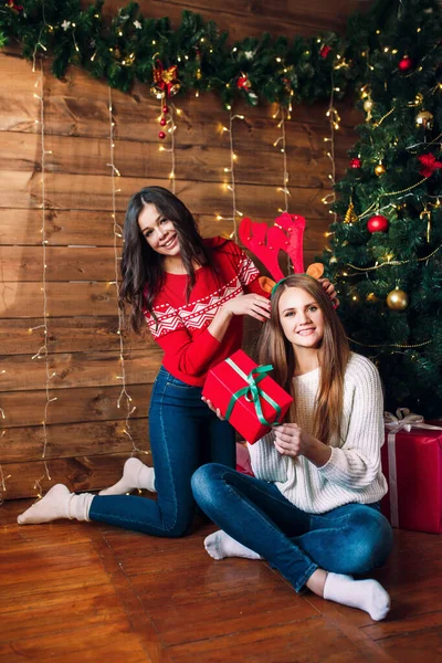 Dwie szczęśliwe młode kobiety trzymające pudełko nad choinką — Zdjęcie stockowe