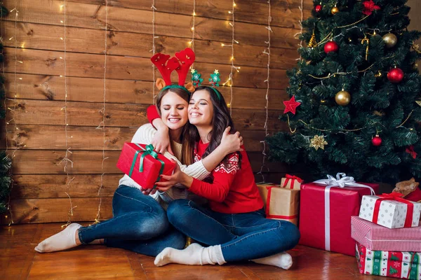Dos hermosas mujeres jóvenes dando un regalo de Navidad entre sí — Foto de Stock