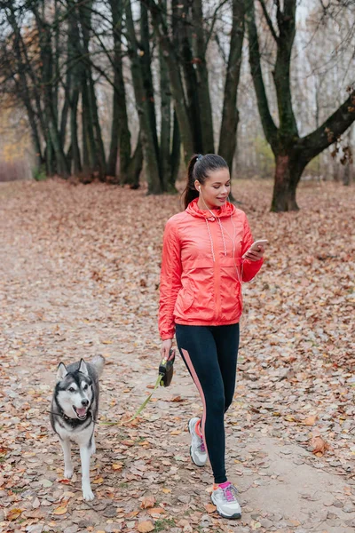 Parkta köpeğiyle yürüyen sağlıklı genç bir kadının tam boy portresi. — Stok fotoğraf