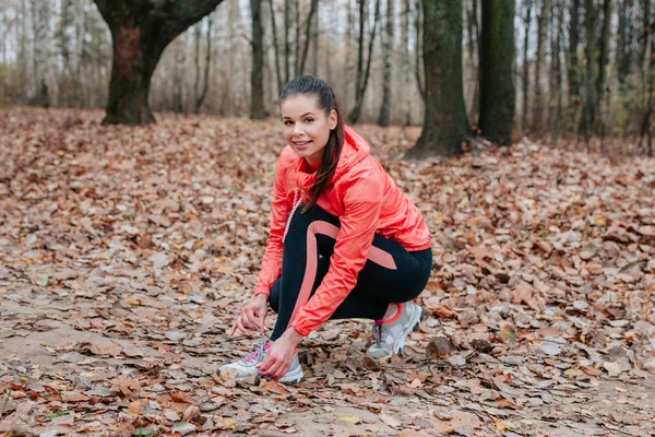 Läuferin bindet Schnürsenkel für Herbstlauf im Waldpark — Stockfoto