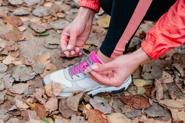 Koşu ayakkabısı koşucusu kadın sonbahar koşusu için bağcıklarını bağlıyor orman parkında — Stok fotoğraf