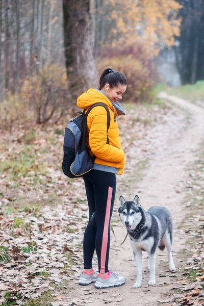 Kvinna går med en hund promenader på hösten i parken — Stockfoto