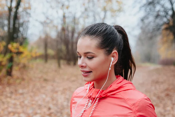 Sportliche junge Frau, die im Park läuft und Musik hört. Sportlicher Lebensstil. — Stockfoto