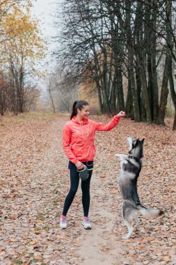 Gülümseyen kadın köpeğine bir emir veriyor.