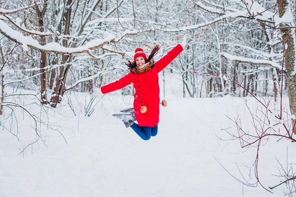 Mujer joven feliz con ropa roja elegante saltando en la nieve al aire libre. Divirtiéndose. Temporada de invierno . —  Fotos de Stock