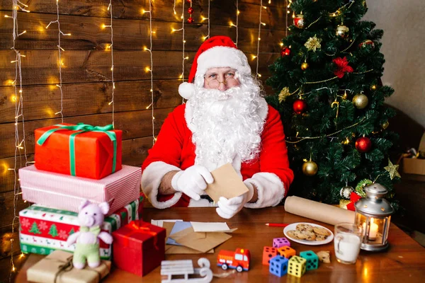 메리 크리스마스 그리고 해피 홀리데이입니다. 산타 클로스 집에서 책상에 크리스마스에 대 한 어린이 위한 선물을 준비 하기. — 스톡 사진