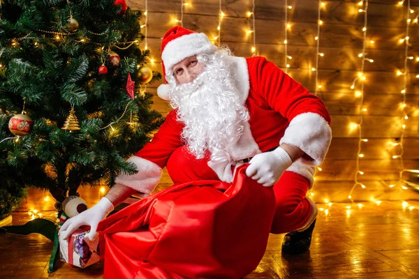 Santa Claus poblíž vánoční stromeček s dárky. Vánoční čas — Stock fotografie