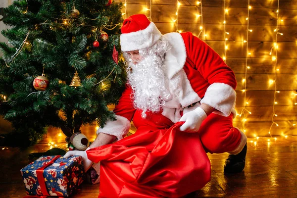 Santa Claus poblíž vánoční stromeček s dárky. Vánoční čas — Stock fotografie