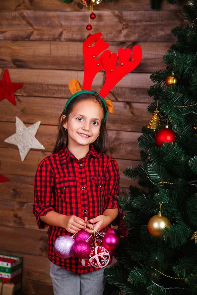 Милая маленькая девочка украшает елку красочными игрушками дома — стоковое фото