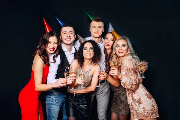 Festa de aniversário de amigos. Seis pessoas se divertindo e bebendo champanhe no fundo preto — Fotografia de Stock