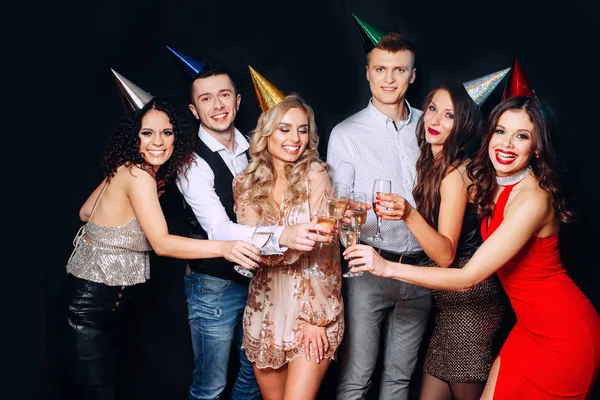 Friends birthday party. Six people having fun and drinking champagne on black background