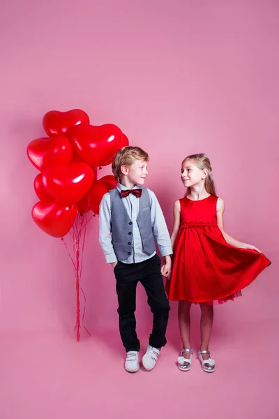 Two children with heart shape air balloons on pink background — 스톡 사진