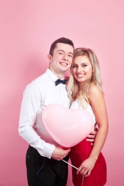 Stüdyo arka planında pembe balonları olan güzel romantik çift.