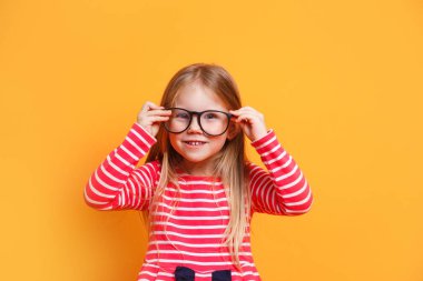 Portrait of young smiling girl wearing glasses on yellow background