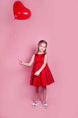 Kalp şeklinde balonu olan kırmızı elbiseli küçük kız.