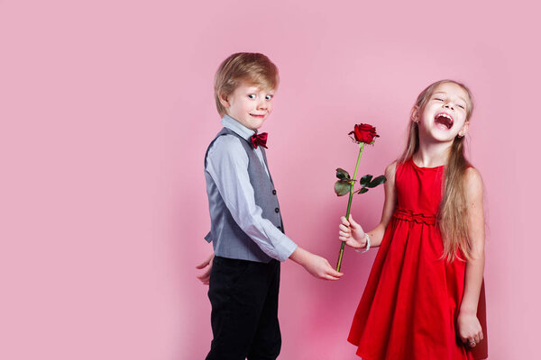 Funny little boy in love giving cute girl red rose , Valentines day surprise